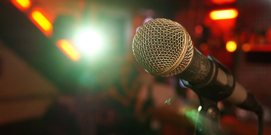 close up view of a microphone with stand on a stage in front of a crowd